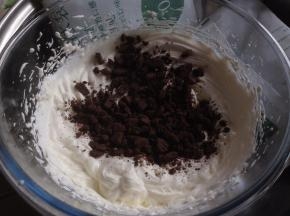 烘烤结束将蛋糕取出，晾2-3分钟，再倒扣在另一张干净的油纸上，撕掉底部油纸，卷一下定型，再摊开。淡奶油加糖隔冰水打发，倒入奥利奥饼干碎，拌均匀