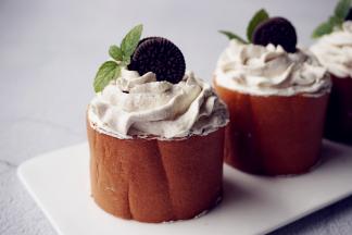 卷起，切成若干等份，切面朝上，挤上淡奶油，放上一块奥利奥饼干和薄荷叶装饰