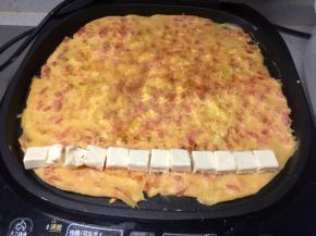 蛋饼煎熟后，在饼的一端放上一排芝士小食块（一个切成两半）