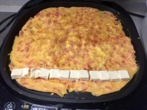 蛋饼煎熟后，在饼的一端放上一排芝士小食块（一个切成两半）
