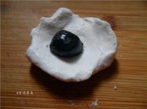 取一小块糯米团，按扁，中间放入芝麻团