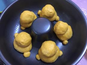 然后将面团放入烤盘中，再放入搓圆的5份18g面团作为头，还有10份2g面团作为脚，揉圆，放入模具中