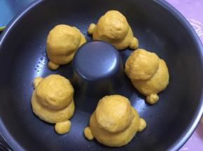 然后将面团放入烤盘中，再放入搓圆的5份18g面团作为头，还有10份2g面团作为脚，揉圆，放入模具中