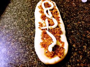 再将醒好的面团擀成长条，铺上肉松，挤适量沙拉酱