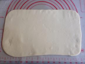 发酵好的面团取出排气，在案板上撒些面粉，将面团擀成长方形