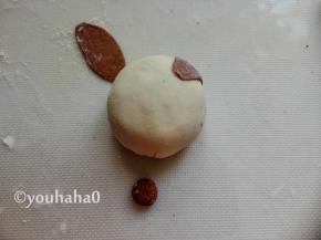 可可面团刷一点点水，粘在豆沙包的上部2端，作为小猪的耳朵