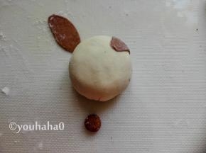 可可面团刷一点点水，粘在豆沙包的上部2端，作为小猪的耳朵