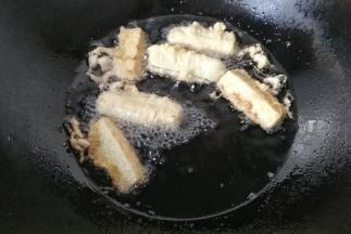 锅中入适量油烧至六七成热，下入挂浆的茄条开始炸