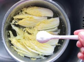 把切开的黄芽菜放入装有清水的盆里，加入一勺盐，浸泡一会儿