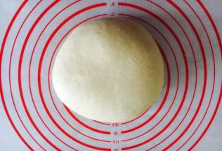 拿出发酵好的面团排气，盖上保鲜膜醒15分钟。