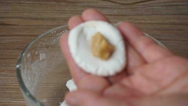 取一块面团团圆，摁扁，加入一块花生馅