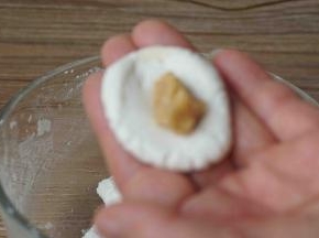 取一块面团团圆，摁扁，加入一块花生馅