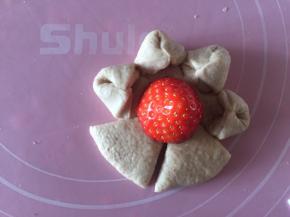 最后一个面团擀成圆形，四周割成6片。捏起。放入半颗草莓做心