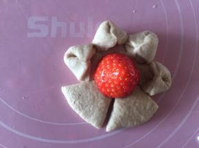 最后一个面团擀成圆形，四周割成6片。捏起。放入半颗草莓做心