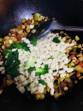 麻食煮熟后，捞出控干水分，倒入炒好的蔬菜中。