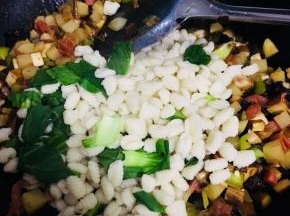 麻食煮熟后，捞出控干水分，倒入炒好的蔬菜中。