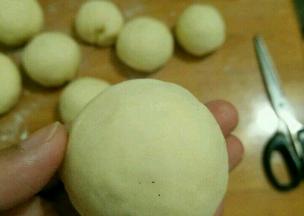 用擀面杖把小块面团擀成中间厚的圆形，放上紫薯馅包好并搓圆。