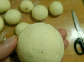 用擀面杖把小块面团擀成中间厚的圆形，放上紫薯馅包好并搓圆。