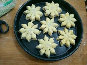 然后在每片花瓣尾部捏一下，全部做好后进行二次发酵，同时烤箱预热。发酵完毕后刷蛋液，在花朵中间位置撒点芝麻。