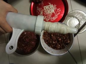 开始灌肠，把肠衣一根套在灌肠器的嘴上，另一头栓个扣或者用棉线系紧，灌肠器肚子里塞上肉馅