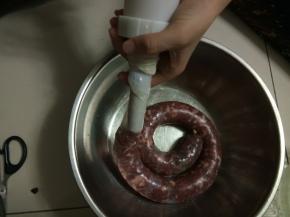 慢慢拧灌肠器上面的螺栓，很容易就把肉灌进去了，如果感觉有灌的松的地方，用手挤压一下，尽量灌紧实一点，如果感觉灌的太紧怕破掉就随时用牙签扎一下灌好的肠体。