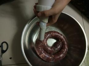 慢慢拧灌肠器上面的螺栓，很容易就把肉灌进去了，如果感觉有灌的松的地方，用手挤压一下，尽量灌紧实一点，如果感觉灌的太紧怕破掉就随时用牙签扎一下灌好的肠体。
