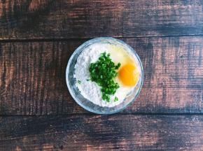 将香葱洗净后切碎，放入面粉碗中，打入一个鸡蛋