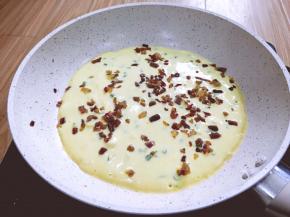 将鸡蛋液分俩次倒入锅中，先到一半，将炒过的香肠丁撒表面