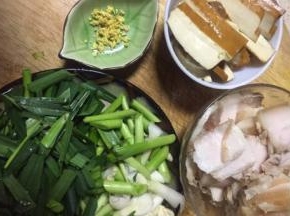 蒜苗理去老叶和根须，蒜苗洗净先用刀拍把蒜苗头斜刀切段，切好的径和叶分开放备用，锅里煮的五花肉用筷子试插入无血水溢出，就捞起来切片，老姜剁末，所有食材都切好备用