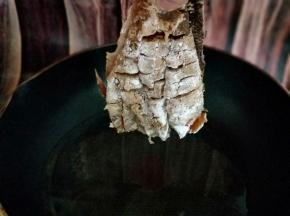 这样，首先拎着鱼尾巴，将热油用勺子往鱼身上淋，这样鱼更容易定型。