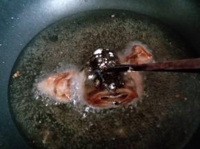 放入油锅中，可以借助筷子压住鱼头，定型。炸至微黄捞出。