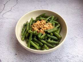 将适量的酱汁倒入煮熟的长豆角里。