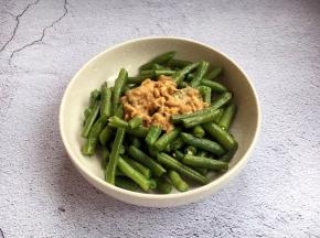 将适量的酱汁倒入煮熟的长豆角里。
