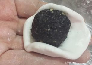 将面团剂子轻轻按压成小碗状，一份面团包住一份内馅，依次包好所有的汤圆，并揉圆，最后滚一圈糯米粉防粘