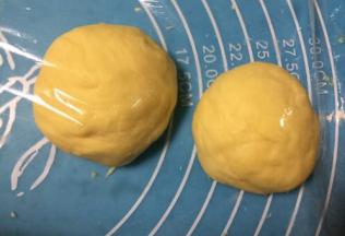 取出面团按压排气揉均匀，把面团分成两份小剂子，盖上保鲜膜醒发15分钟