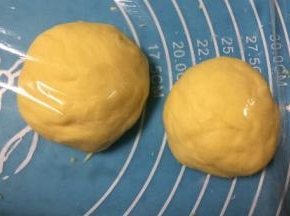 取出面团按压排气揉均匀，把面团分成两份小剂子，盖上保鲜膜醒发15分钟