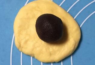 醒好的面剂子擀成圆形，红豆沙馅放在不居中的位置