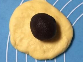 醒好的面剂子擀成圆形，红豆沙馅放在不居中的位置