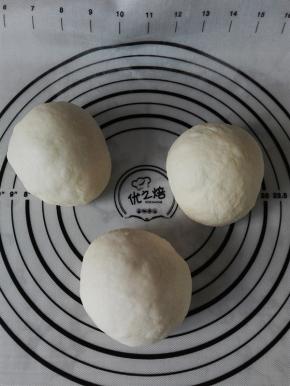 取出发酵后的面团，按压排气，分割为均等的3份，滚圆，盖保鲜膜醒发20分钟