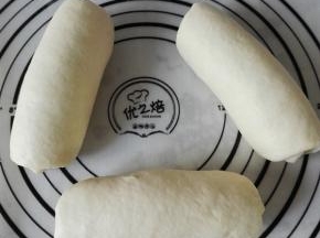 取一个醒发后的面团按扁、翻面、上下擀长，自上而下卷起，依次做完3个面团，盖保鲜膜继续醒发20分钟