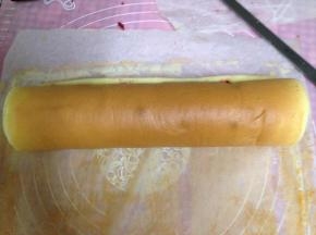 借助擀面杖将蛋糕卷起，包裹油纸定型30分钟