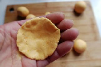 取一个糯米团先用手掌压扁，然后把四周用手捏薄，使其成四周薄中间厚的形状