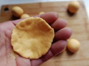 取一个糯米团先用手掌压扁，然后把四周用手捏薄，使其成四周薄中间厚的形状