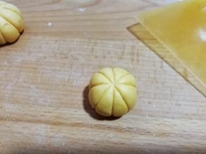 然后用刮板呈“米”字形，在糯米团上压出南瓜形花纹（操作时左手拿糯米团，右手拿刮板从上往下轻轻推挤着压出花纹，一个人拍照不好拍出此步骤细节）