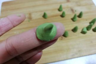 再把底部捏薄，凹成一个图钉形状，抹点水沾在南瓜汤圆团上