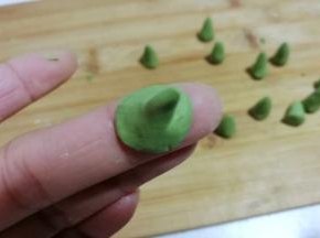 再把底部捏薄，凹成一个图钉形状，抹点水沾在南瓜汤圆团上