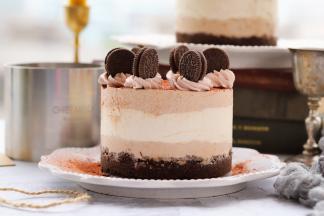 在慕斯表面筛上可可粉，打发好的可可淡奶油用8齿的裱花嘴在挤出花纹装饰，放上迷你的奥利奥饼干