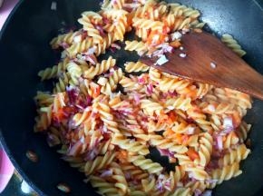 放入洋葱，翻炒，使每一个意面都粘上茄汁。