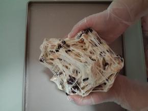 待稍凉后，戴上PVC一次性手套，将糖取出放到不沾烤盘上。把整个糖团从中间掰开往下翻，再换个角度从中间掰开往下翻。重复几次。会扯出很多糖丝，糖丝会将所有干性材料包裹入其中。