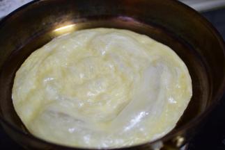 锅加热，将速冻手抓饼从冰箱拿出来直接放在预热好的锅里，中火煎，锅中不用放油，等手抓饼鼓起来